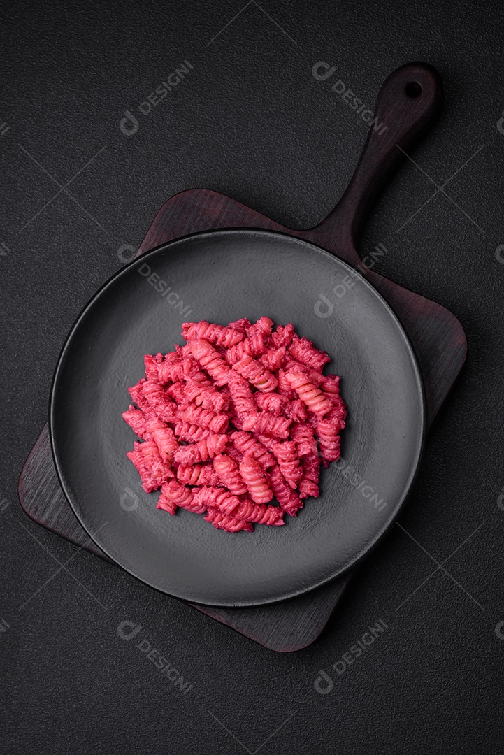 Deliciosa massa fusilli com pesto de beterraba, parmesão, sal e especiarias sobre um fundo escuro de concreto