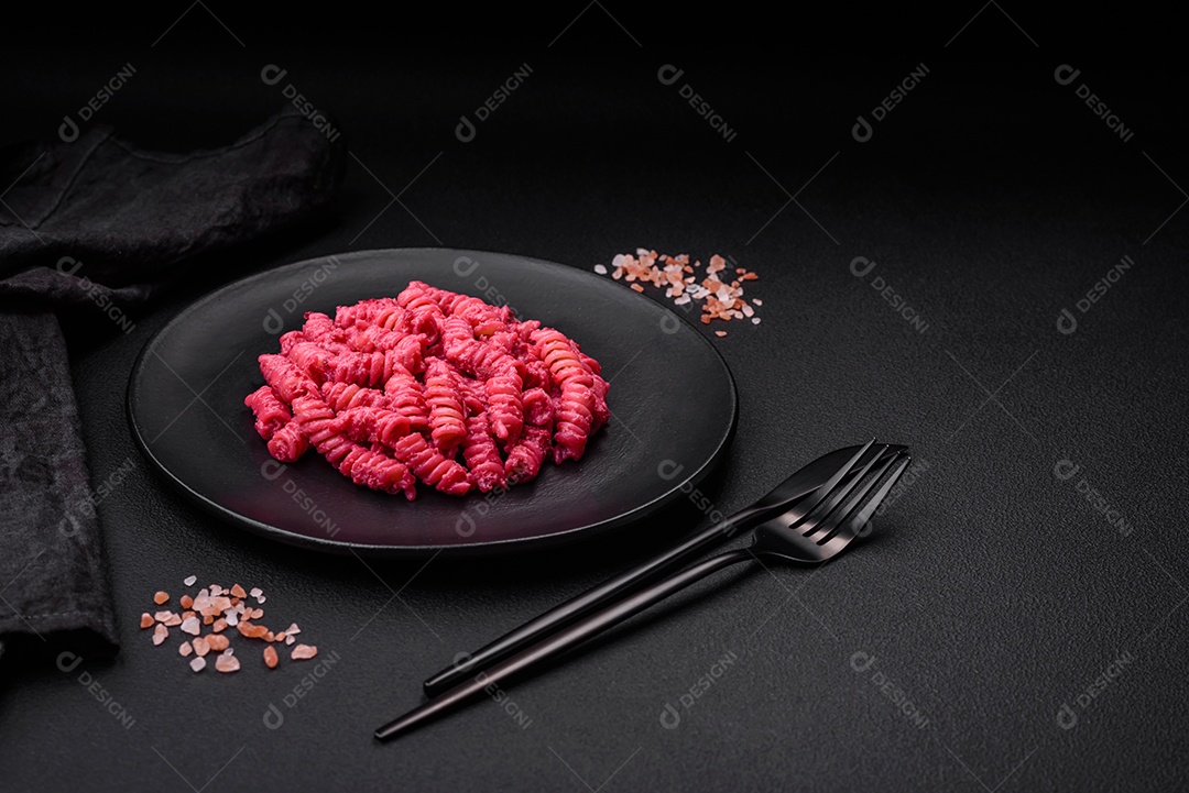 Deliciosa massa fusilli com pesto de beterraba, parmesão, sal e especiarias sobre um fundo escuro de concreto