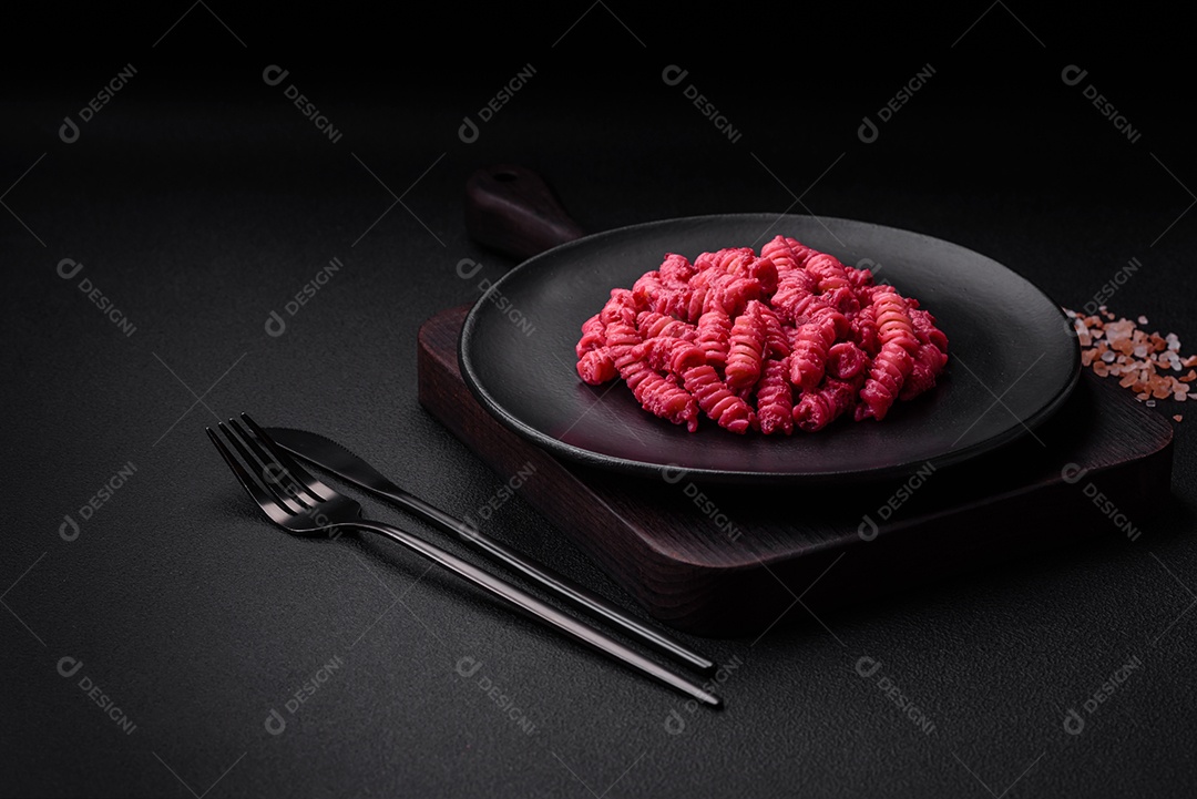Deliciosa massa fusilli com pesto de beterraba, parmesão, sal e especiarias sobre um fundo escuro de concreto