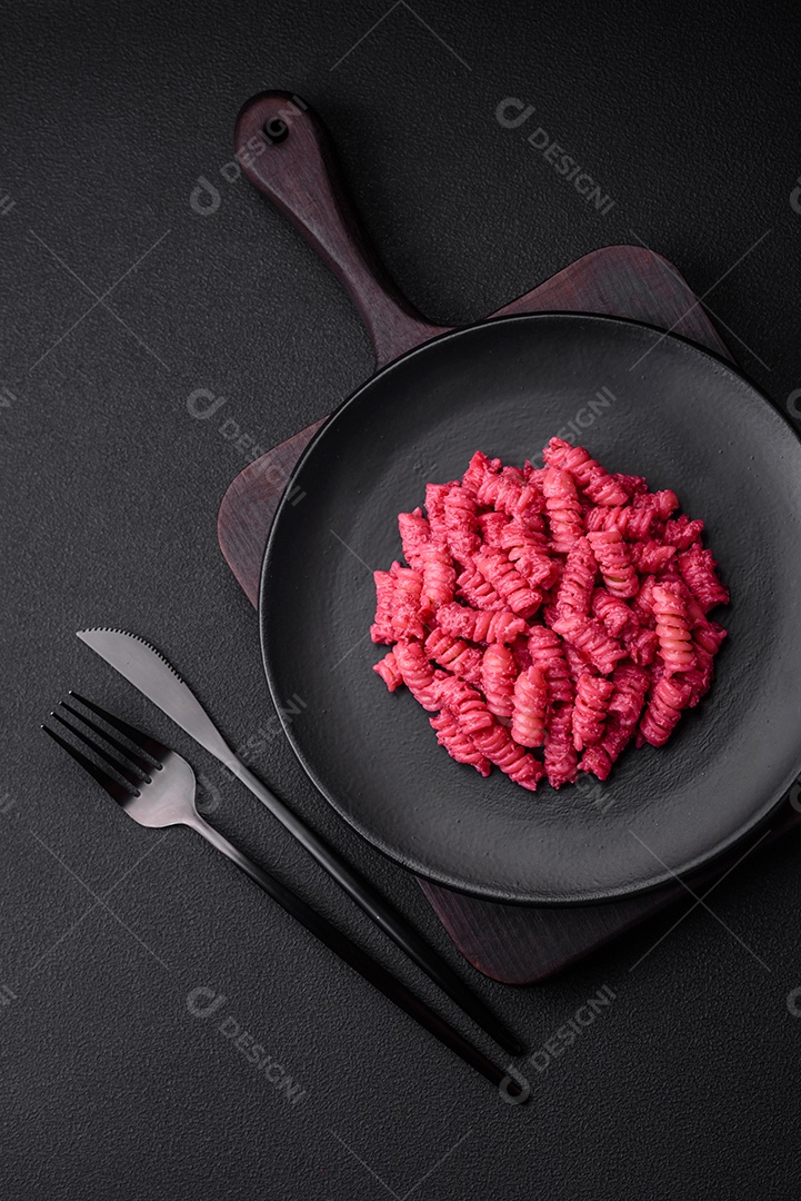 Deliciosa massa fusilli com pesto de beterraba, parmesão, sal e especiarias sobre um fundo escuro de concreto