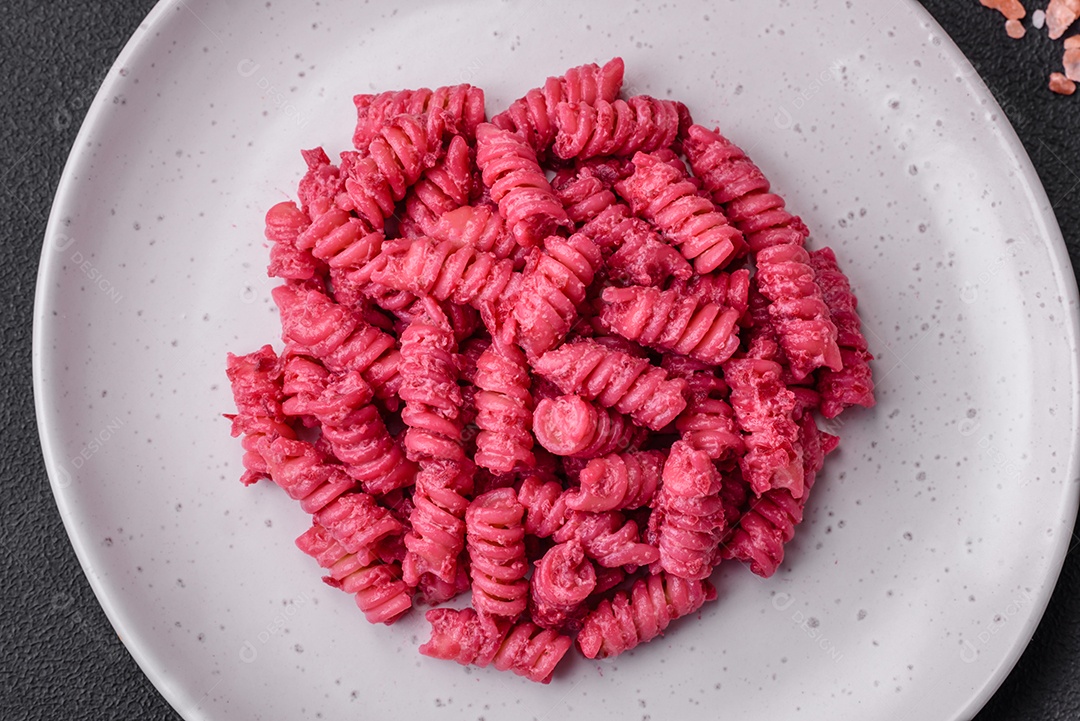 Deliciosa massa fusilli com pesto de beterraba, parmesão, sal e especiarias sobre um fundo escuro de concreto