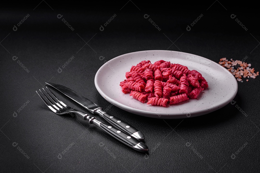 Deliciosa massa fusilli com pesto de beterraba, parmesão, sal e especiarias sobre um fundo escuro de concreto