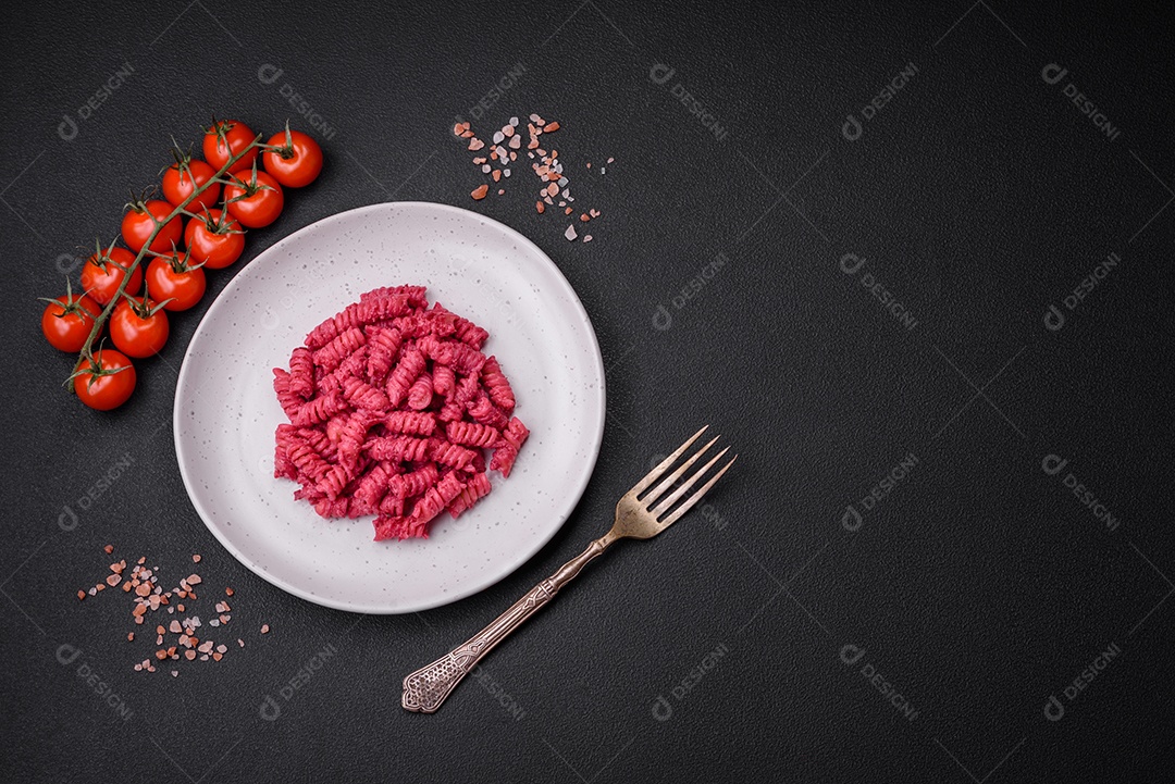 Deliciosa massa fusilli com pesto de beterraba, parmesão, sal e especiarias sobre um fundo escuro de concreto