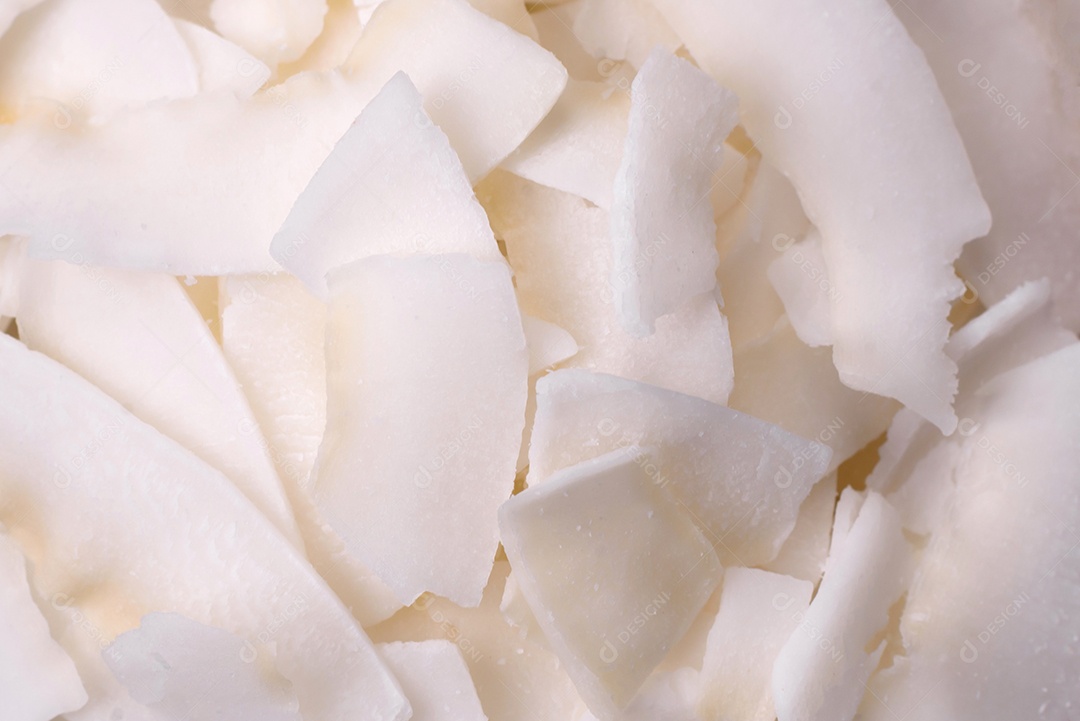 Flocos de coco branco seco em uma tigela de madeira preparada para fazer sobremesas sobre um fundo de concreto texturizado