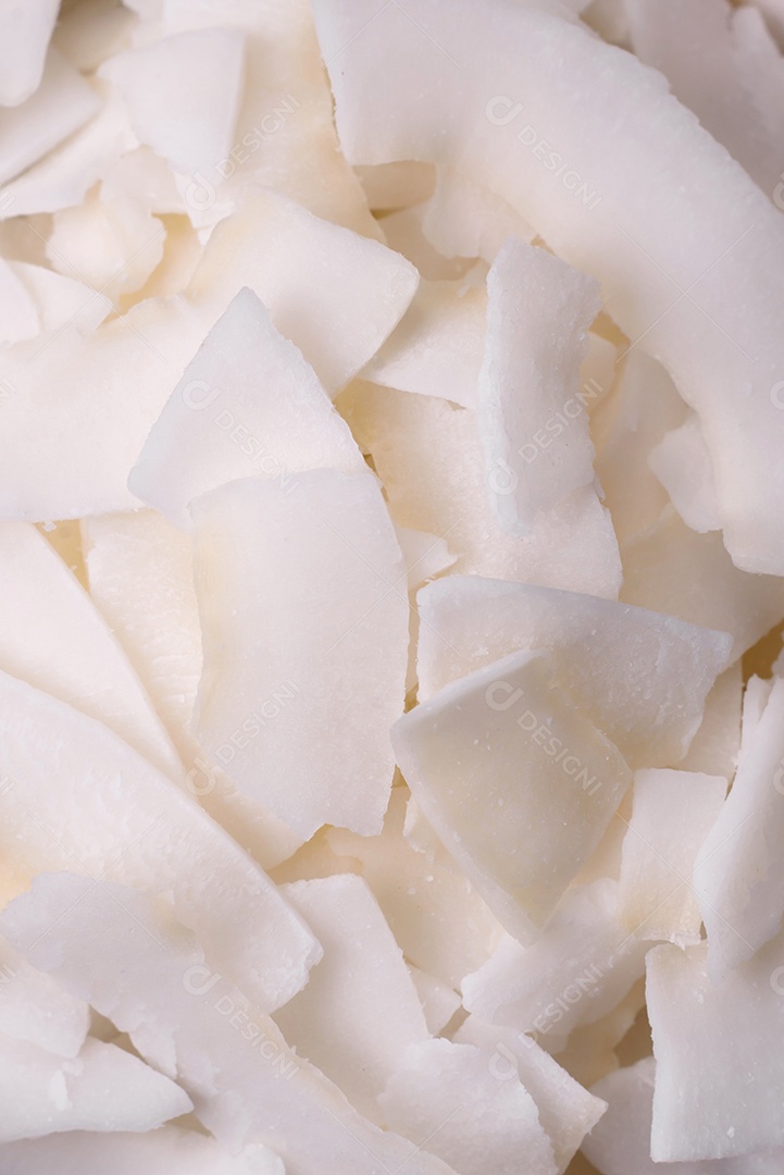 Flocos de coco branco seco em uma tigela de madeira preparada para fazer sobremesas sobre um fundo de concreto texturizado