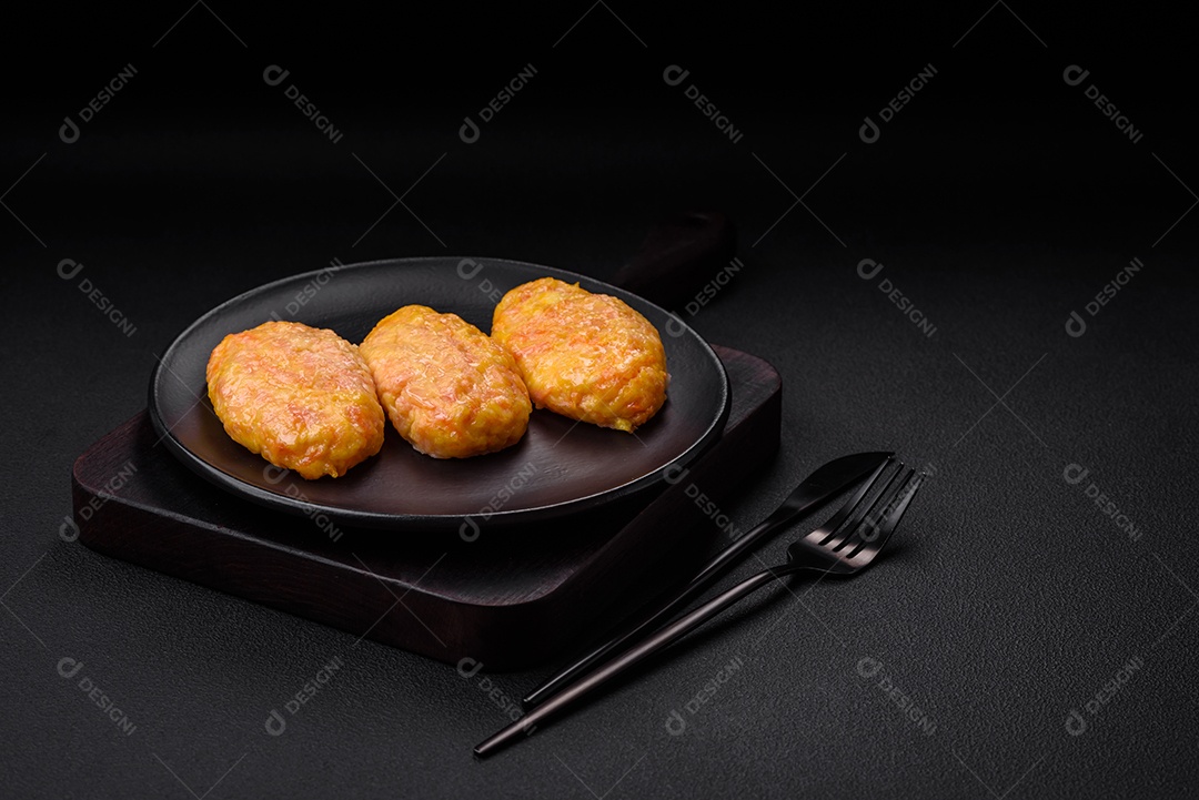 Deliciosas costeletas de vapor com cenoura, queijo, sal e especiarias sobre um fundo escuro de concreto