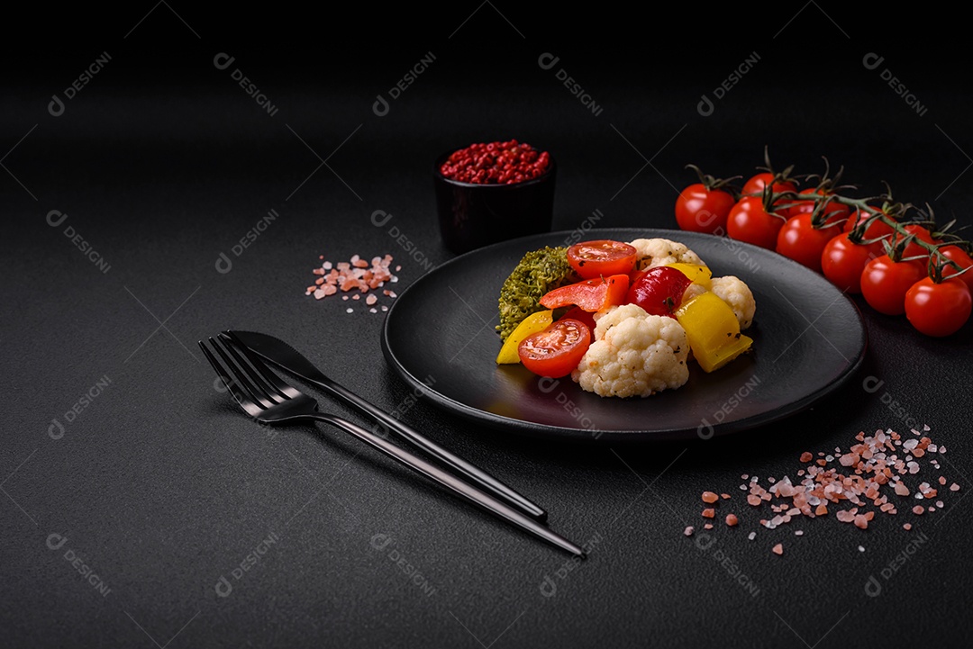 Deliciosa salada fresca de brócolis, couve-flor, pimentão e tomate cereja com especiarias e sal sobre um fundo escuro de concreto
