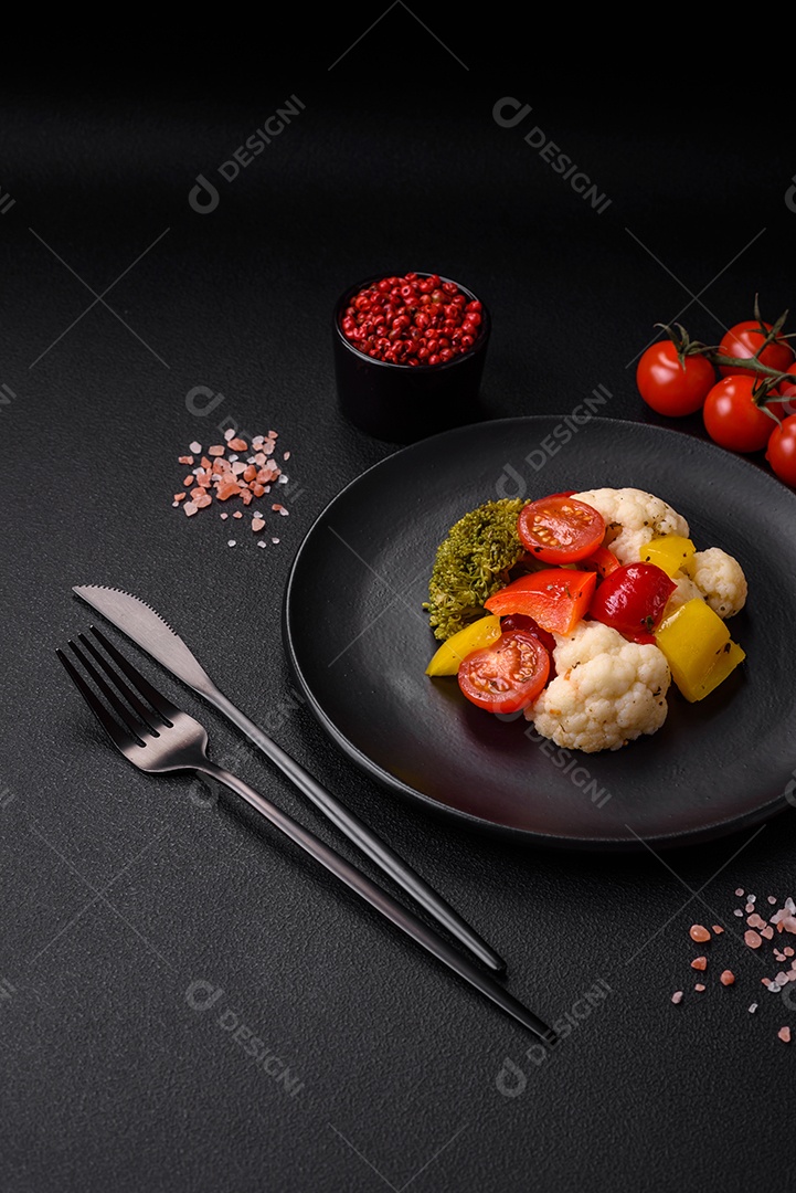 Deliciosa salada fresca de brócolis, couve-flor, pimentão e tomate cereja com especiarias e sal sobre um fundo escuro de concreto