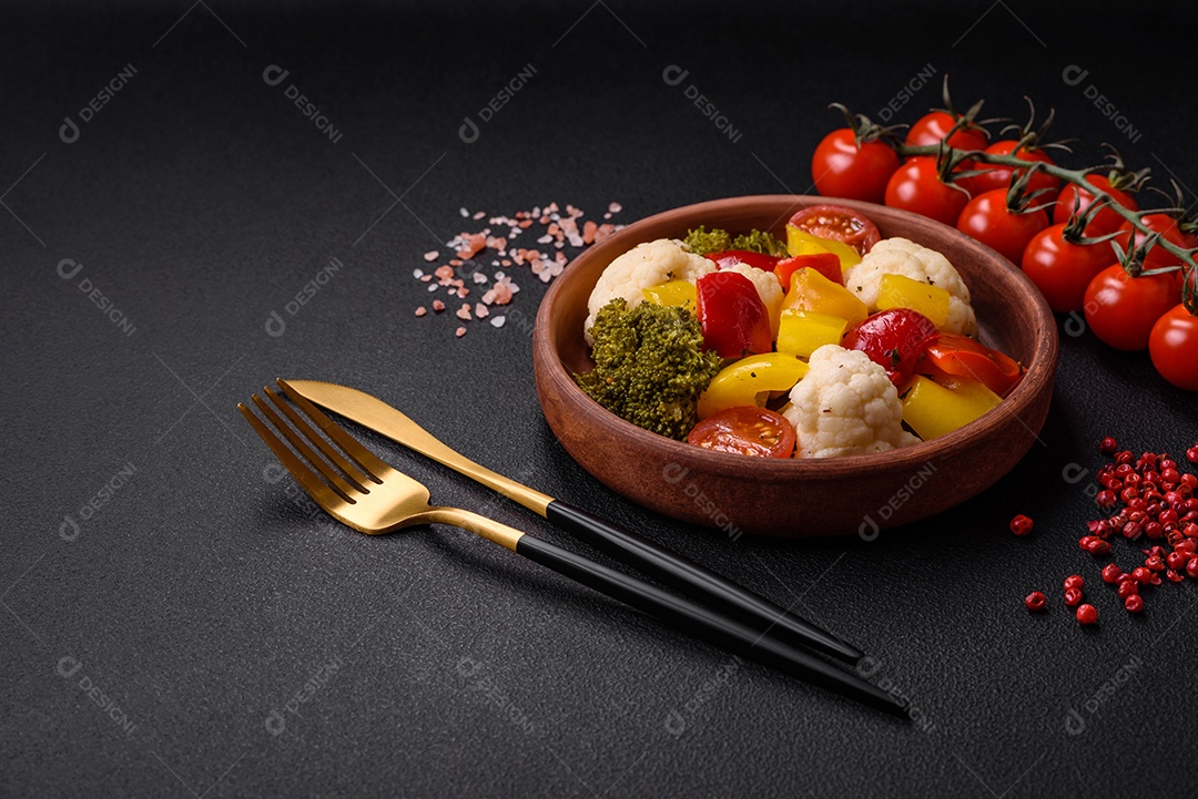 Deliciosa salada fresca de brócolis, couve-flor, pimentão e tomate cereja com especiarias e sal sobre um fundo escuro de concreto