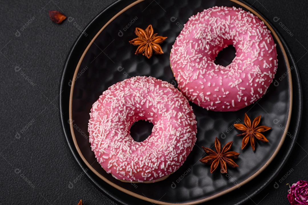 Deliciosos donuts doces frescos em esmalte rosa com recheio de morango sobre um fundo escuro de concreto