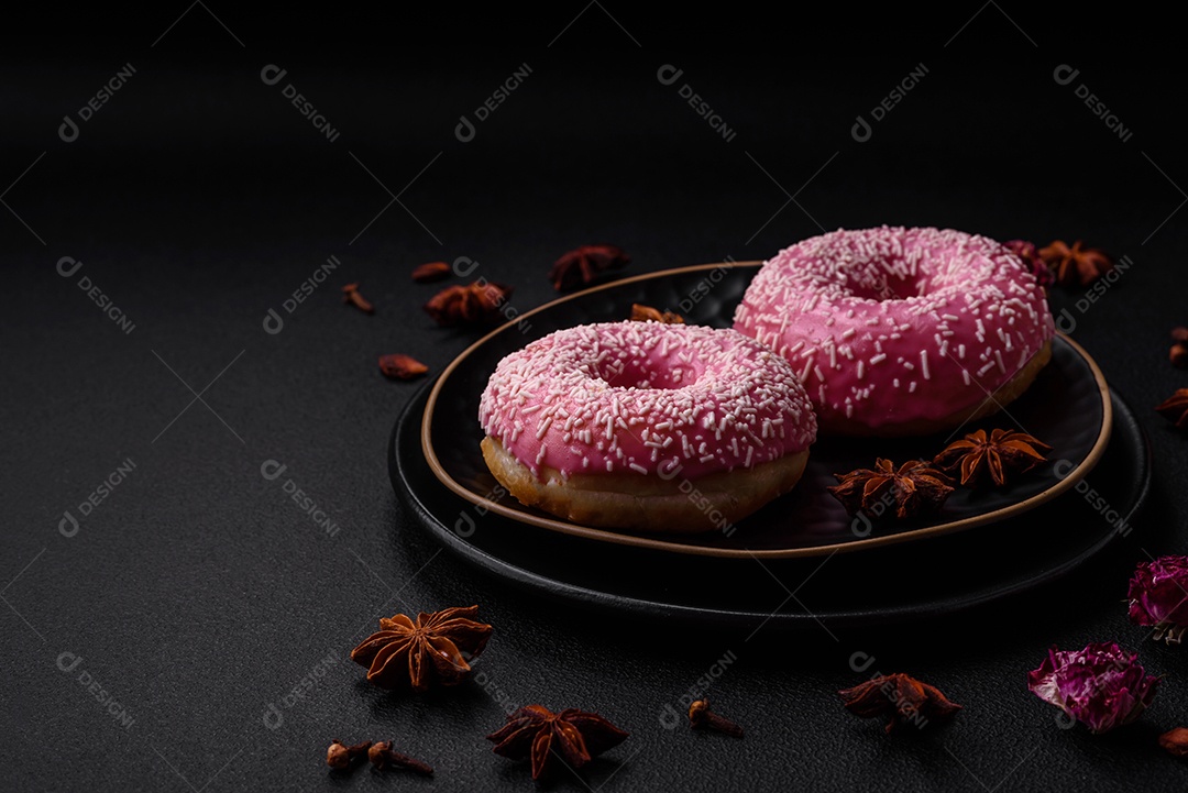 Deliciosos donuts doces frescos em esmalte rosa com recheio de morango sobre um fundo escuro de concreto