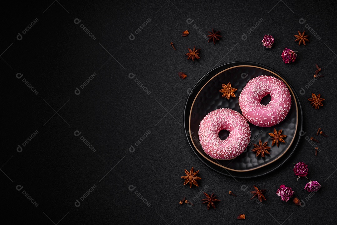 Deliciosos donuts doces frescos em esmalte rosa com recheio de morango sobre um fundo escuro de concreto