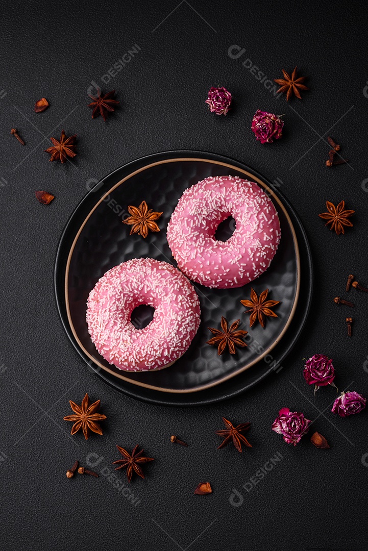 Deliciosos donuts doces frescos em esmalte rosa com recheio de morango sobre um fundo escuro de concreto