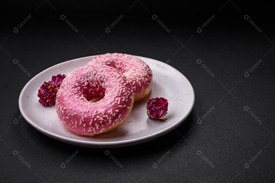 Deliciosos donuts doces frescos em esmalte rosa com recheio de morango sobre um fundo escuro de concreto