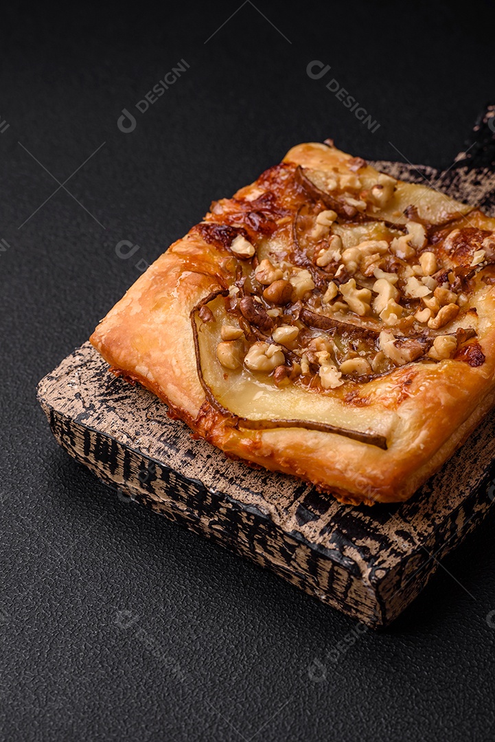 Deliciosa torta doce fresca ou pizza com pera, queijo brie, mel e nozes sobre um fundo escuro de concreto