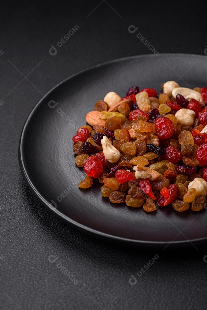Mistura de cajus torrados, avelãs e nozes com cranberries secas e passas sobre um fundo escuro