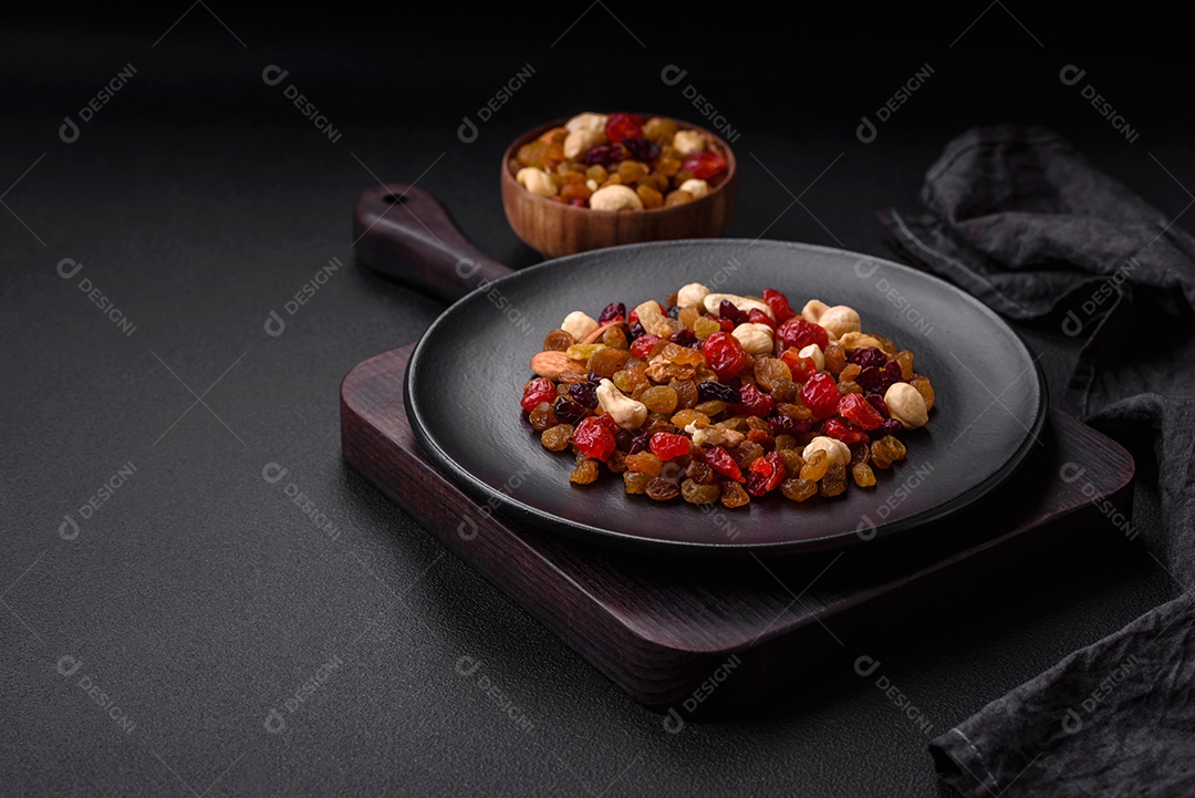 Mistura de cajus torrados, avelãs e nozes com cranberries secas e passas sobre um fundo escuro