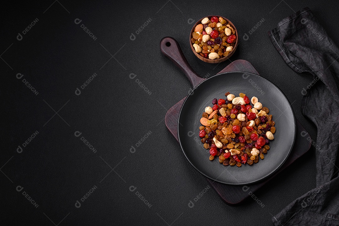 Mistura de cajus torrados, avelãs e nozes com cranberries secas e passas sobre um fundo escuro