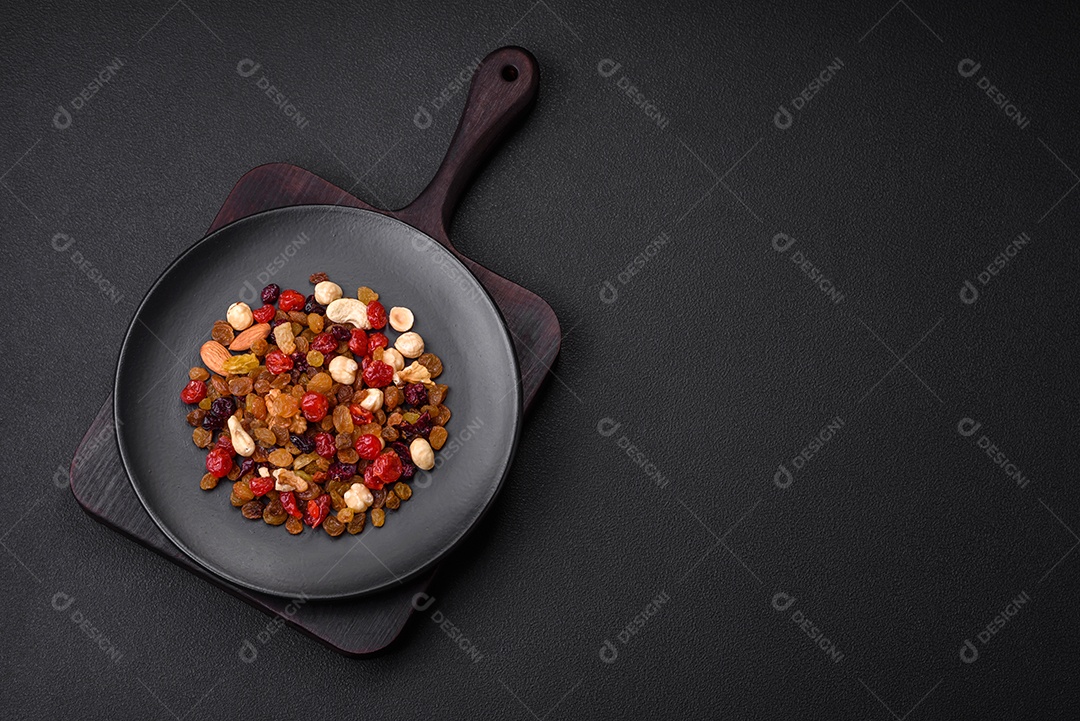 Mistura de cajus torrados, avelãs e nozes com cranberries secas e passas sobre um fundo escuro