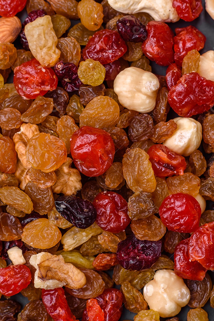 Mistura de cajus torrados, avelãs e nozes com cranberries secas e passas sobre um fundo escuro