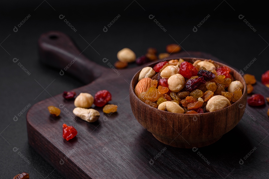Mistura de cajus torrados, avelãs e nozes com cranberries secas e passas sobre um fundo escuro