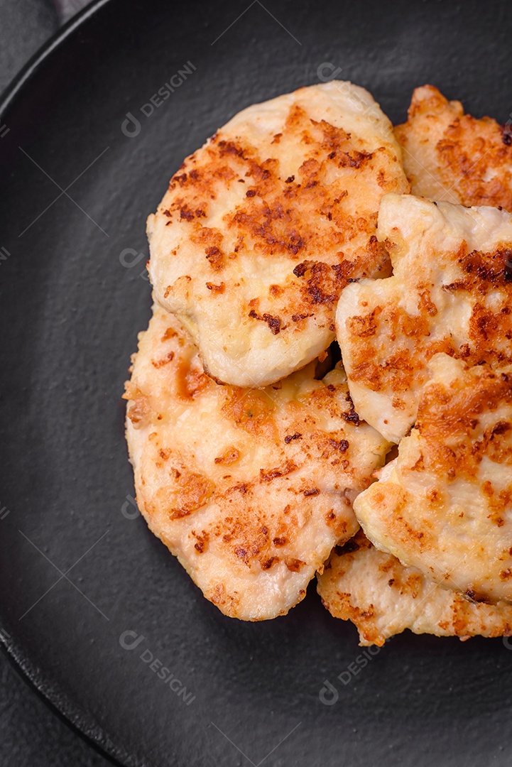 Deliciosas costeletas de frango frito com especiarias, sal e ervas sobre um fundo escuro de concreto