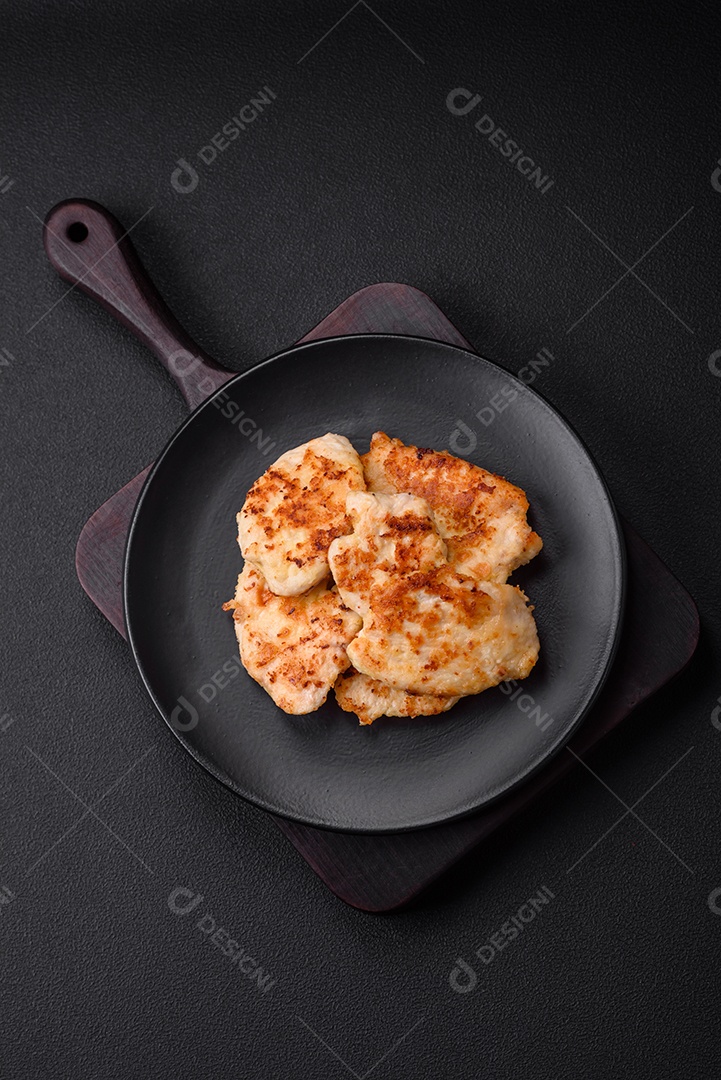 Deliciosas costeletas de frango frito com especiarias, sal e ervas sobre um fundo escuro de concreto