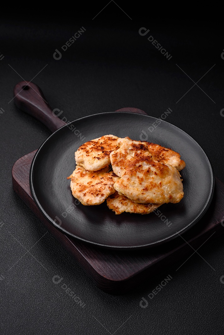 Deliciosas costeletas de frango frito com especiarias, sal e ervas sobre um fundo escuro de concreto