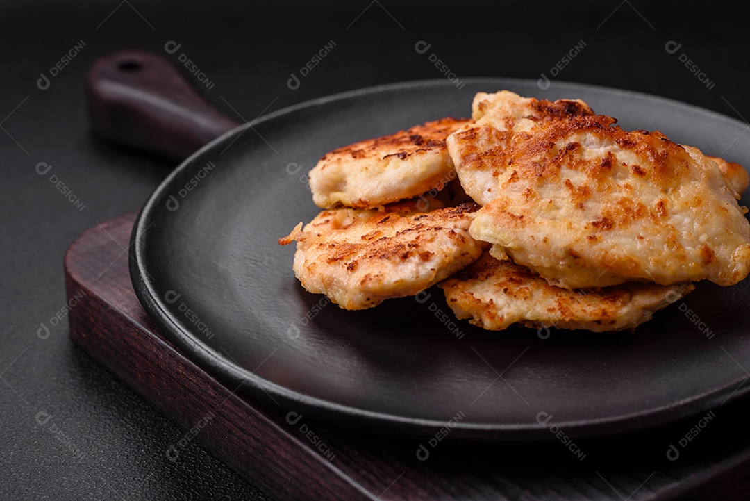 Deliciosas costeletas de frango frito com especiarias, sal e ervas sobre um fundo escuro de concreto