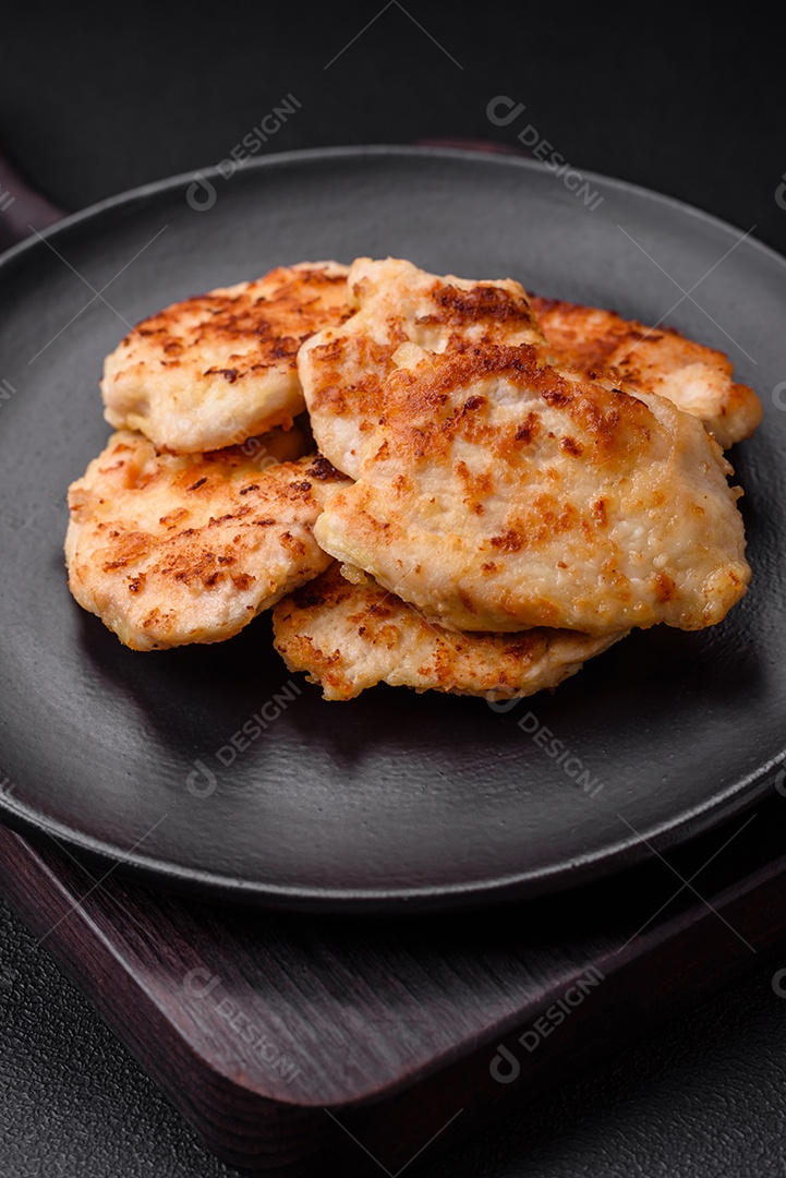 Deliciosas costeletas de frango frito com especiarias, sal e ervas sobre um fundo escuro de concreto
