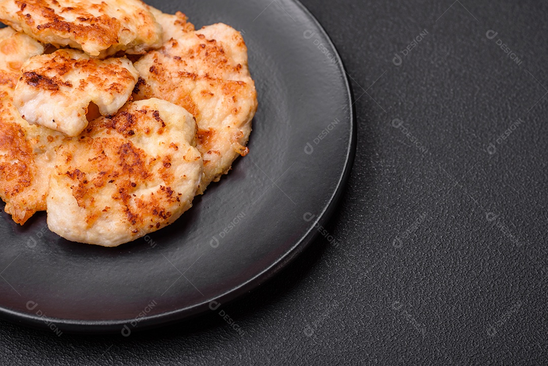 Deliciosas costeletas de frango frito com especiarias, sal e ervas sobre um fundo escuro de concreto