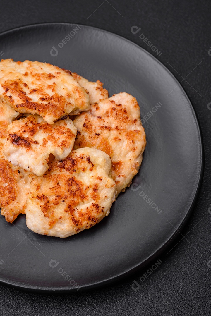 Deliciosas costeletas de frango frito com especiarias, sal e ervas sobre um fundo escuro de concreto