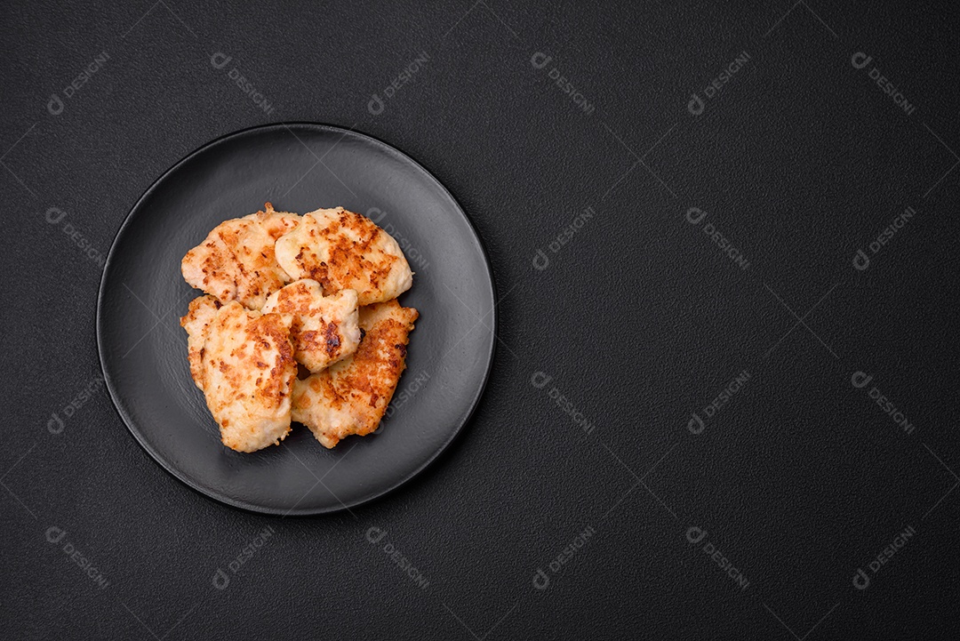 Deliciosas costeletas de frango frito com especiarias, sal e ervas sobre um fundo escuro de concreto