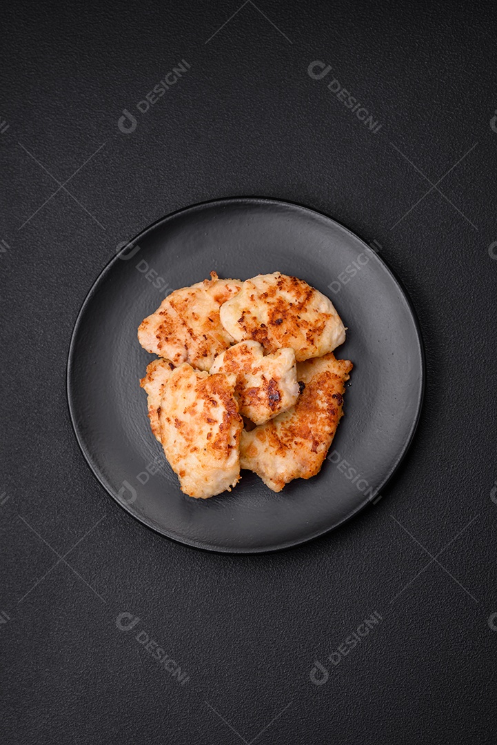 Deliciosas costeletas de frango frito com especiarias, sal e ervas sobre um fundo escuro de concreto