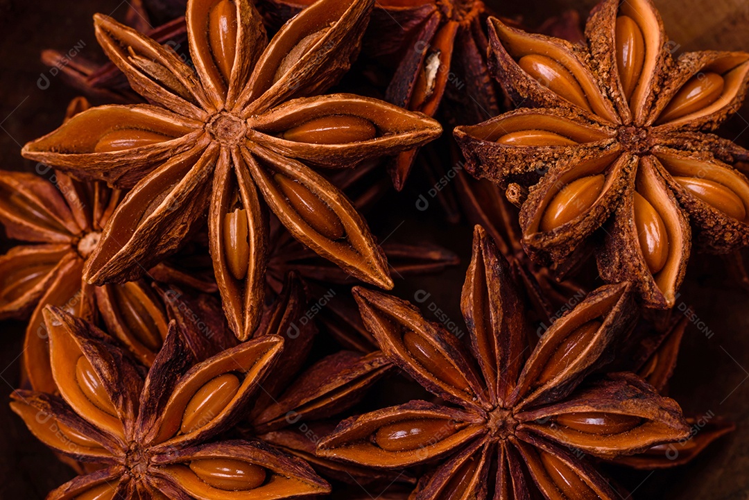 Anis estrelado em forma de estrela em uma tigela redonda de madeira sobre um fundo escuro de concreto