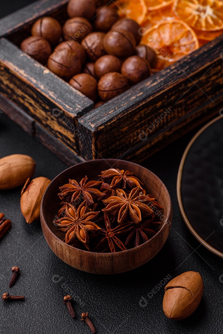 Nozes torradas e nozes de macadâmia, tangerina seca, frutos secos sobre um fundo escuro de concreto