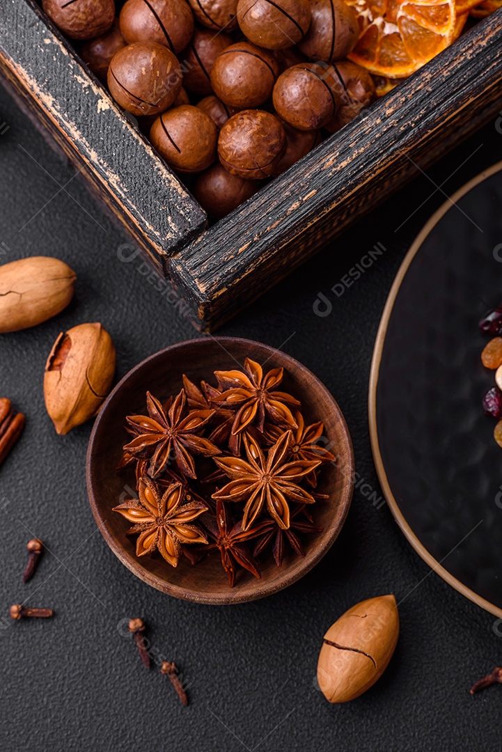 Nozes torradas e nozes de macadâmia, tangerina seca, frutos secos sobre um fundo escuro de concreto