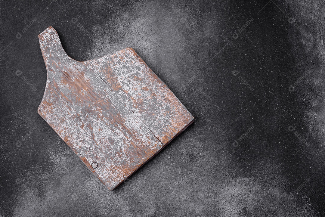 Tábua de corte de madeira vazia com rachaduras e arranhões localizados em um fundo escuro de concreto