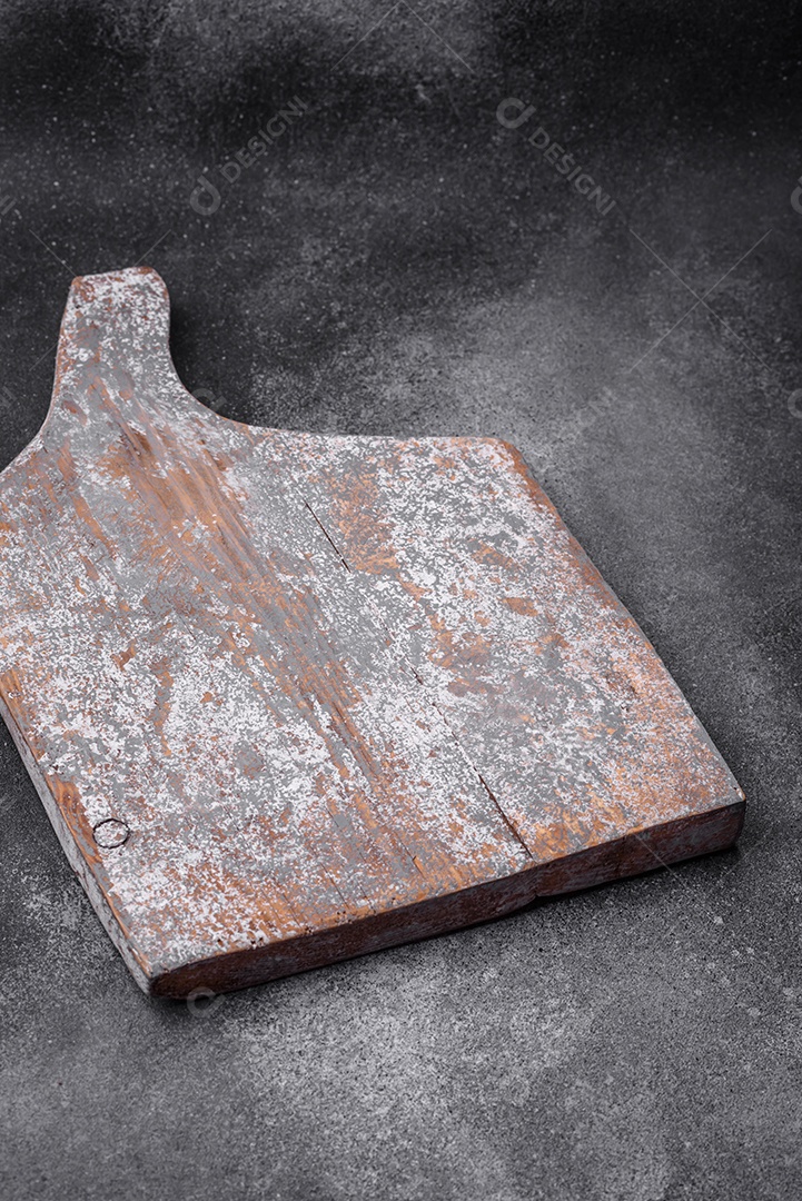 Tábua de corte de madeira vazia com rachaduras e arranhões localizados em um fundo escuro de concreto