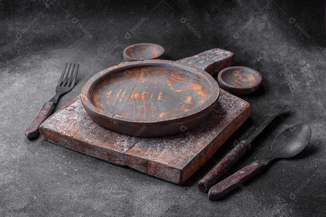 Prato de madeira vazio, faca, garfo e tábua de corte em fundo de concreto texturizado