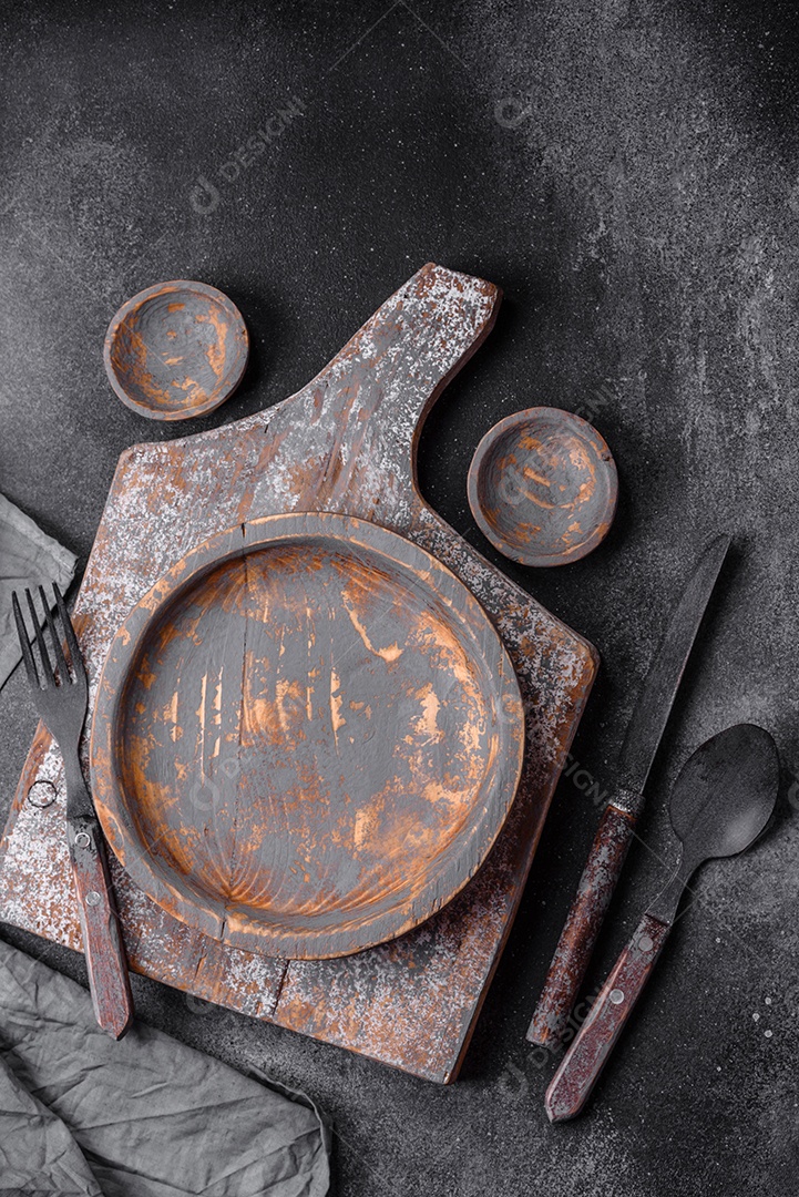 Prato de madeira vazio, faca, garfo e tábua de corte em fundo de concreto texturizado