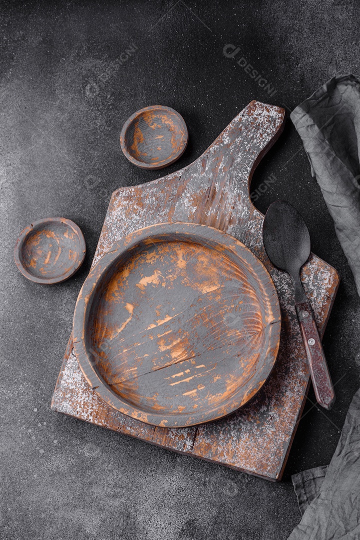 Prato de madeira vazio, faca, garfo e tábua de corte em fundo de concreto texturizado