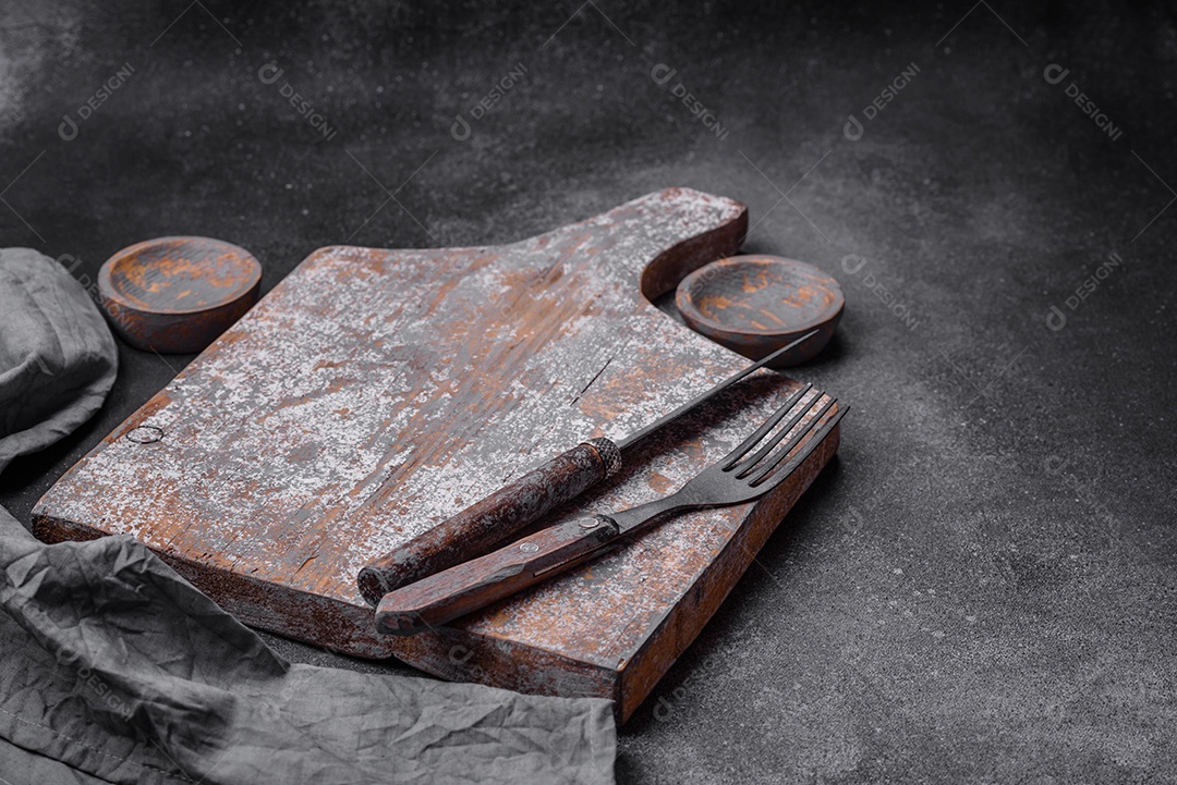 Prato de madeira vazio, faca, garfo e tábua de corte em fundo de concreto texturizado