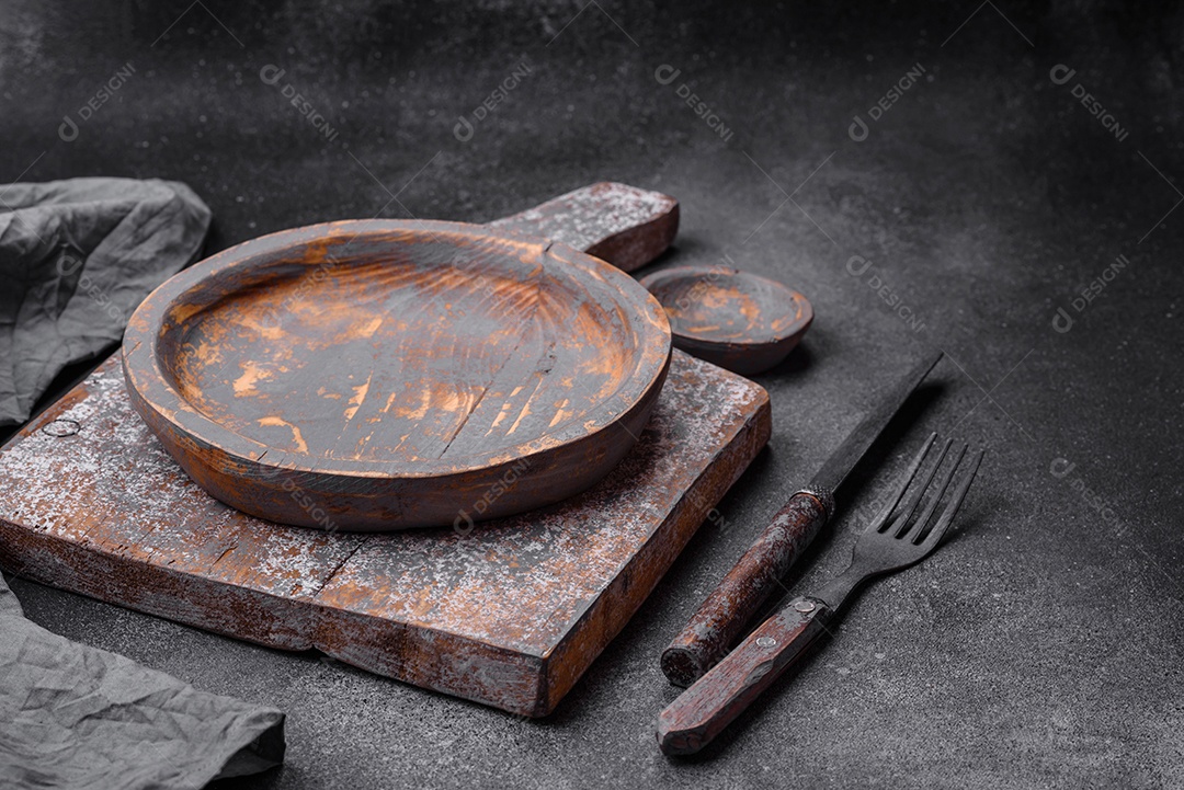 Prato de madeira vazio, faca, garfo e tábua de corte em fundo de concreto texturizado