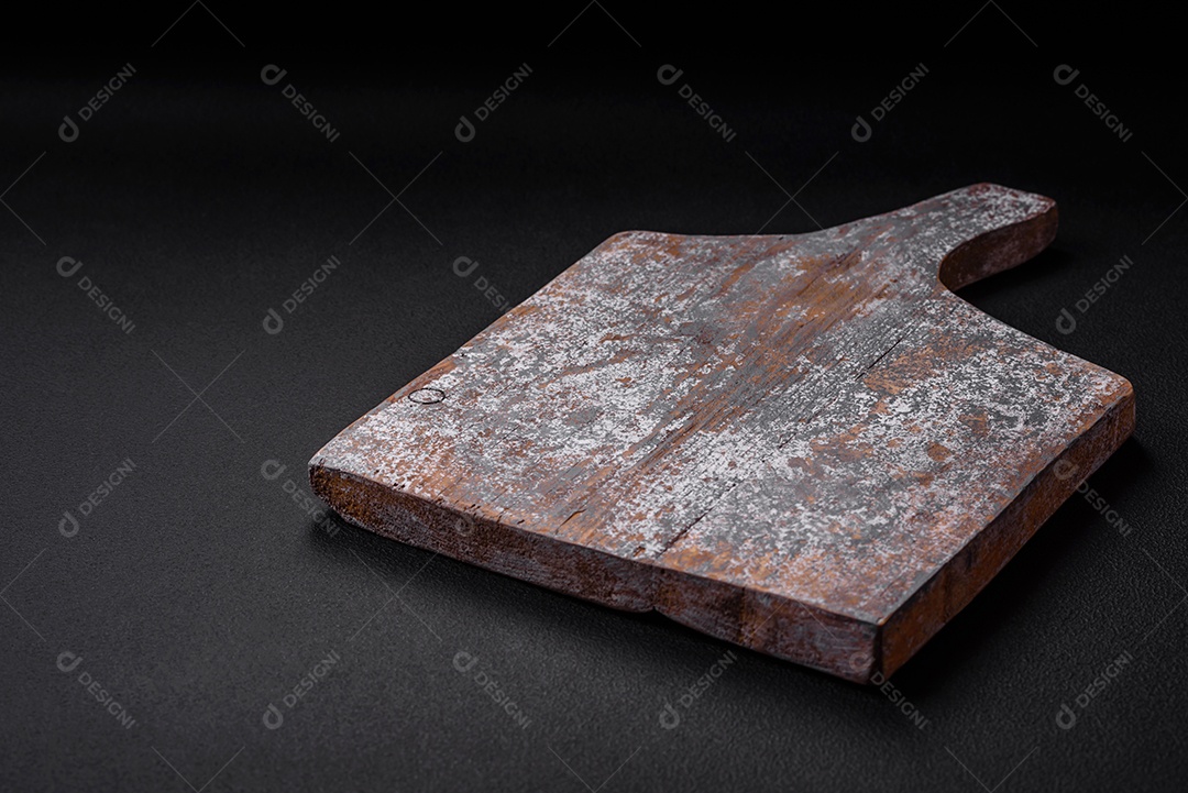 Tábua de corte de madeira vazia com rachaduras e arranhões localizados em um fundo escuro de concreto