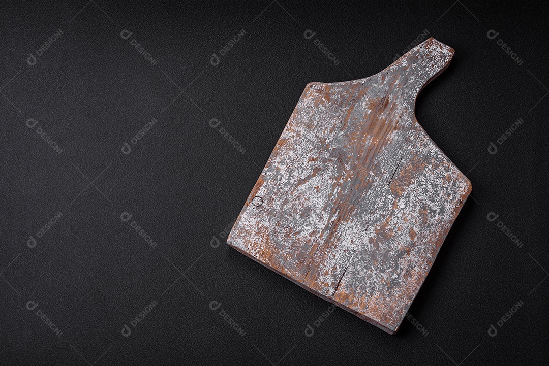 Tábua de corte de madeira vazia com rachaduras e arranhões localizados em um fundo escuro de concreto