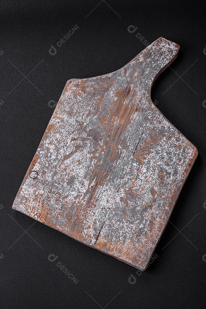 Tábua de corte de madeira vazia com rachaduras e arranhões localizados em um fundo escuro de concreto