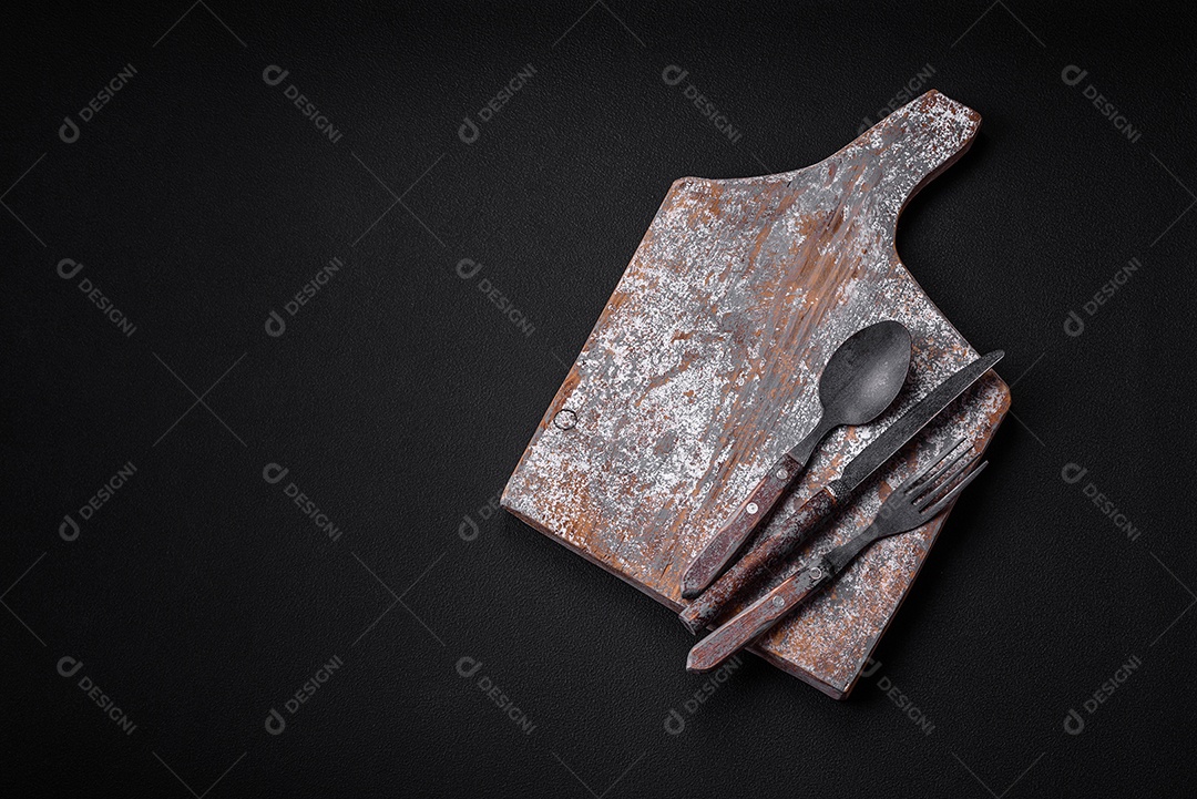 Tábua de corte de madeira vazia com rachaduras e arranhões localizados em um fundo escuro de concreto