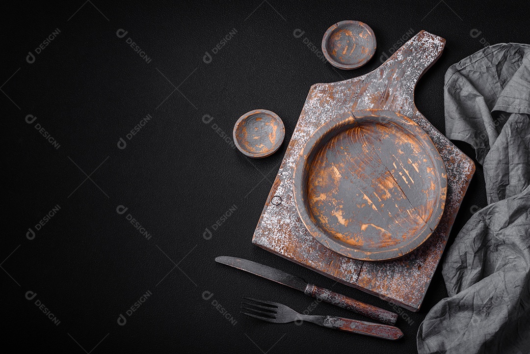 Prato de madeira vazio, faca, garfo e tábua de corte em fundo de concreto texturizado