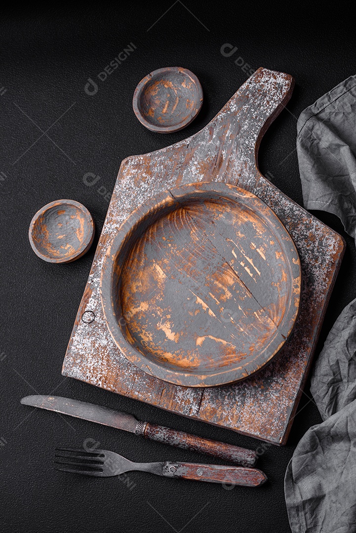 Prato de madeira vazio, faca, garfo e tábua de corte em fundo de concreto texturizado